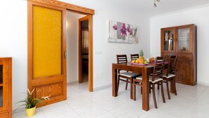 Un coin repas avec une table et des chaises en bois, un meuble avec des portes en verre et un tableau accroché au mur.