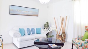 Een moderne woonkamer met een witte bank, een zwarte salontafel en een kleurrijke stoel.
