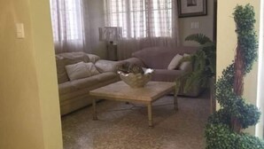 A living room with a beige sofa, a coffee table, and a ceiling fan. - Gorgeous House in the Center of Santiago (Santiago De Los Caballeros)