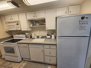 A kitchen with white cabinets, a microwave, stove, and refrigerator.