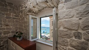 A stone-walled room with a window overlooking a marina. - Modern apt in the Stone House in the Very Center (Kastela)