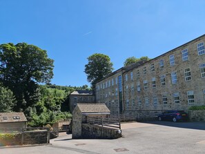 Un bâtiment en pierre doté de nombreuses fenêtres et d’une cour dallée.