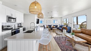 A modern kitchen with white cabinetry, stainless steel appliances, and a central island with bar stools. - Private Beach Walkover, Sunset Views & Room to Gather (Surfside Beach)