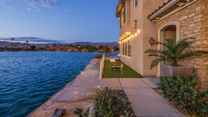 A waterfront property with a patio, outdoor seating, and a view of the water and mountains. - Lakefront Dream: Misters and The Best Corner Lot on the Lake! EV! (Indio)