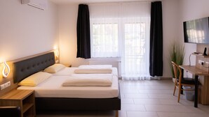 A hotel room with a bed, bedside tables, a desk, a chair, a TV, and a potted plant. - Gap Hotel  (Langwedel)