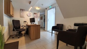 A modern office with a desk, chairs, a computer, and a clock on the wall. - Gap Hotel  (Langwedel)