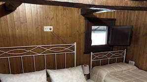 Ein Zimmer mit Holzwänden, einem Bett, einem Nachttisch, einer Lampe und einem Fenster.