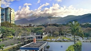 Un quartier résidentiel doté d’une piscine, offrant une vue sur les montagnes et où l’on aperçoit une grue de construction au loin.