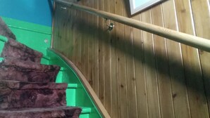A wooden staircase with a metal handrail, green walls, and a framed picture on the wall.