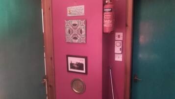 Eine rosa Wand mit einem Feuerlöscher, einem gerahmten Bild und einer Dekoteller.