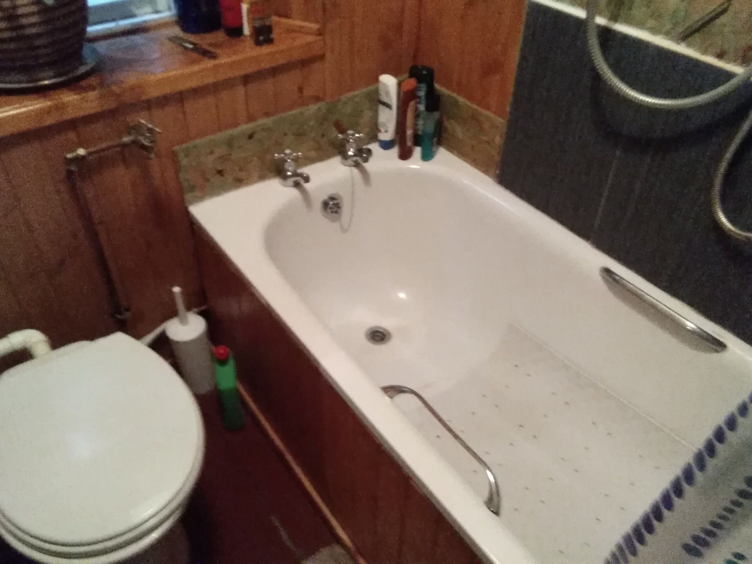 Ein Badezimmer mit einer weißen Badewanne, einer Toilette und einem Ablagefach mit Toilettenartikeln.