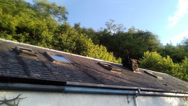 A building with a sloped roof, a chimney, and a small window.