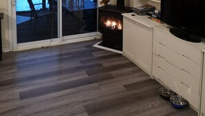 A living room with a fireplace, a television, and a view of a snowy outdoor area through a sliding glass door.