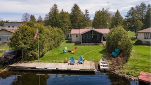 A lakeside property with a dock, outdoor seating, and a small boat.