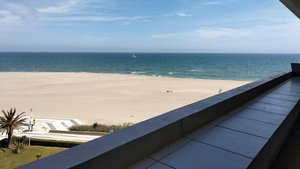 A beach view from a balcony with a clear sky, a sandy beach, and a sailboat in the distance. - Appt 1ère Ligne 2 Terrasses 3 Chambres Accés Direct à la Plage (Canet-en-Roussillon)