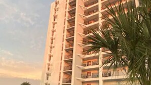 A multi-story hotel with balconies, a swimming pool, and lush greenery.