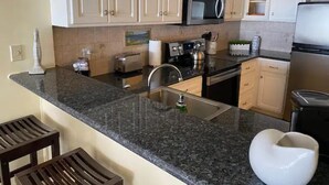 A kitchen with granite countertops, a microwave, a toaster, and a sink.