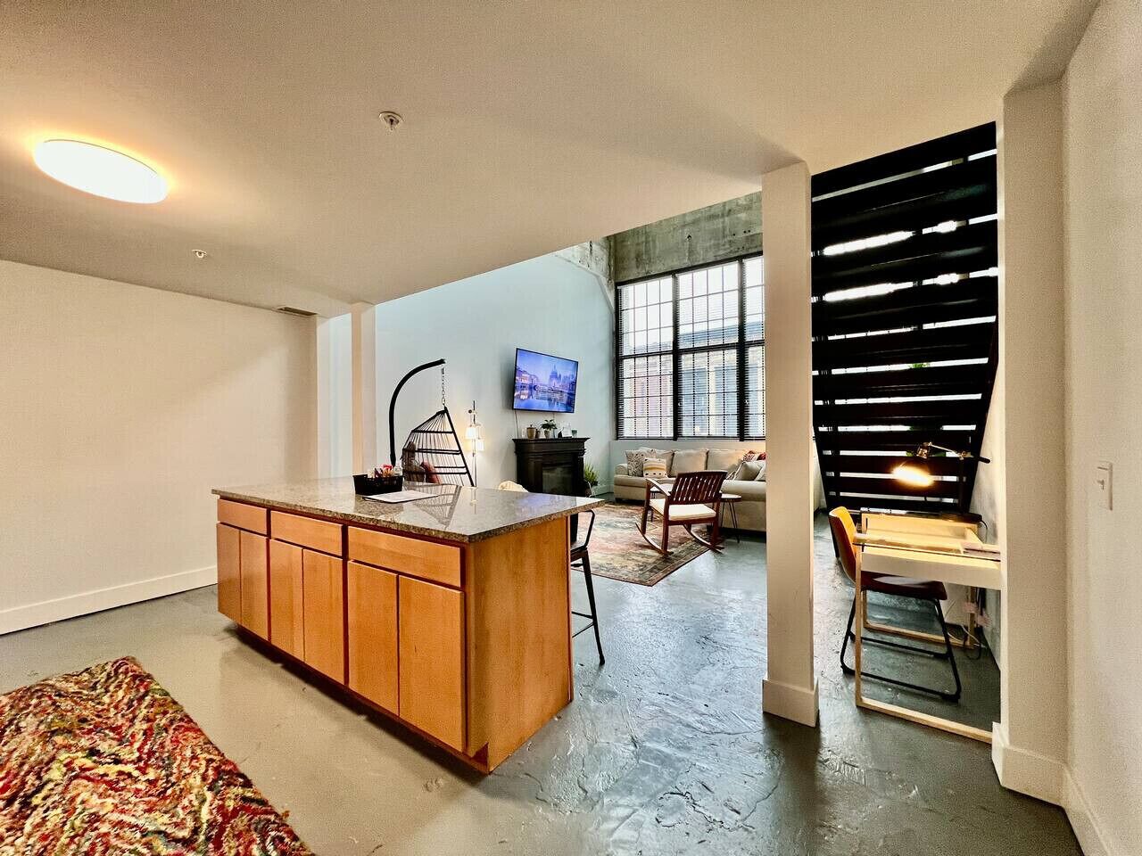 A modern kitchen with a central island, a dining area with a table and chairs, and a living space with a sofa and TV.