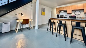 Una cucina moderna con un bancone, un tavolo da pranzo con sedie e una scala.