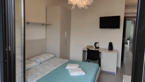 Een hotelkamer met een bed, een bureau, een stoel, een televisie en een kitchenette.