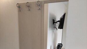 Een kamer met een houten deur, een spiegel en een zwarte lamp op een witte plank.