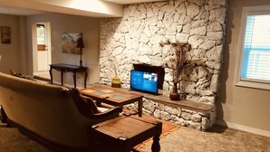 Ein Wohnzimmer mit Steinwand, Flachbildfernseher, Sofa und Couchtisch.