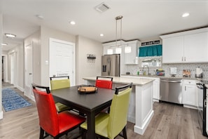 Enjoy meals in this stylish kitchen and dining area, featuring a stainless steel refrigerator, dishwasher, and geometric-patterned backsplash.