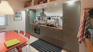 Eine kompakte Küche mit Essbereich, ausgestattet mit Kühlschrank, Herd und verschiedenen Küchenutensilien.
