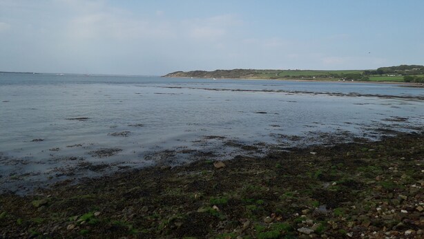 A coastal landscape with a beach, rocky shore, and distant hills. - 3-bedroom Caravan at Thorness bay (Cowes)