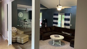 A living room with a sectional sofa, a round coffee table, and a ceiling fan. - The Blue Lagoon on the 18th hole!  Walk to pool, food,  and golf! (Fairfield Bay)