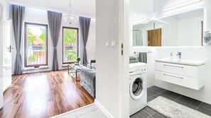 A modern apartment with a living area, a washing machine, and a bathroom with a large mirror. - Apartments Ostsee Swinoujscie (Świnoujście)