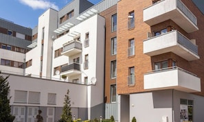 Ein modernes Mehrfamilienhaus mit Balkonen, Satellitenschüsseln und einem verschlossenen Eingang.