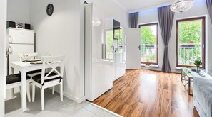 A modern living room with a dining area, wooden flooring, and large windows offering a view of greenery. - Apartments Ostsee Swinoujscie (Świnoujście)