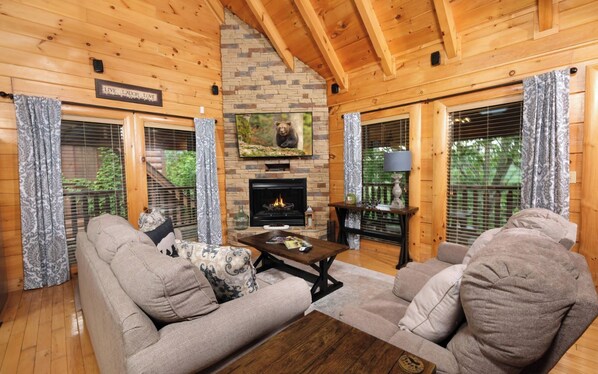 A cozy cabin interior with a fireplace, wooden walls, and a comfortable seating area.