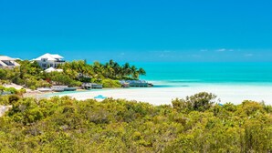 A coastal property with multiple buildings, a beach, and lush greenery. - Beautiful Home by Taylor Bay Beach (Providenciales)