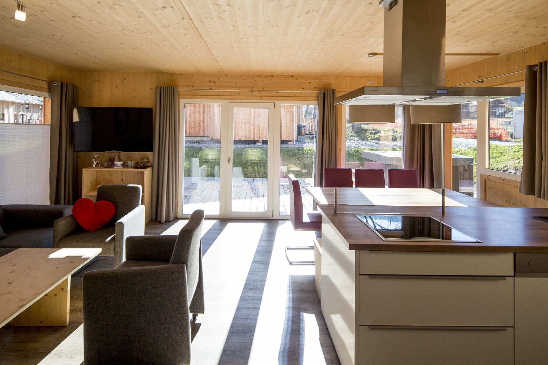 Una cocina moderna con una isla central, un comedor con mesa y sillas, y un rincón de estar acogedor con sofá y cojines.