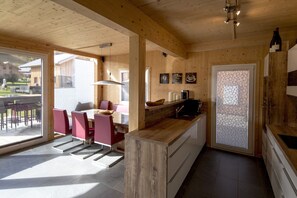 Un interno in legno con zona pranzo, cucina e vista all'esterno.