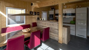 Una cucina moderna con pareti in legno, una zona pranzo con sedie rosse e un frigorifero.