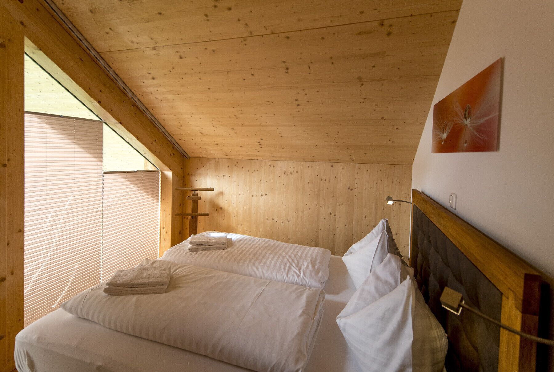 Una habitación con paneles de madera, dos camas, una ventana con persianas y una lámpara de pared.