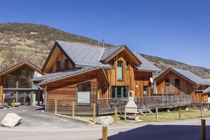 A wooden cabin with a sloped roof, a porch, and a stone fireplace.