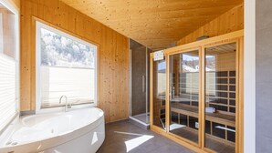 Ein modernes Badezimmer mit freistehender Badewanne, einer Glasdusche und Holzwänden.