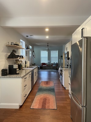 A modern kitchen with white cabinets, a stainless steel refrigerator, and a granite countertop.
