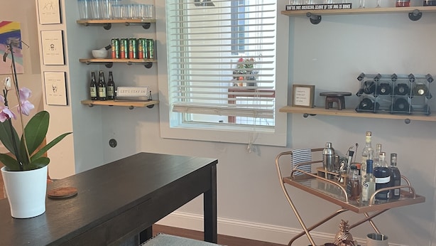 Una cocina moderna con armarios de madera, una encimera oscura y un carrito bar con botellas.
