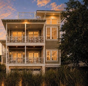A multi-story coastal house with balconies, large windows, and a view of the sea.