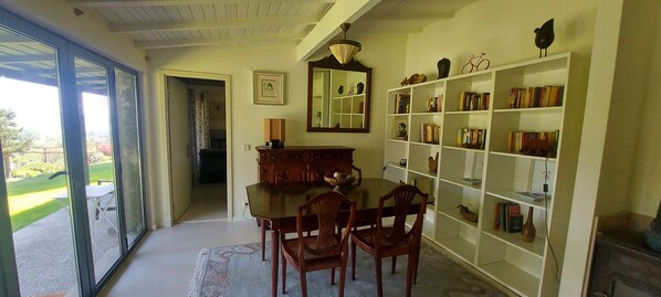 Un comedor con una mesa, sillas, una estantería y un espejo.