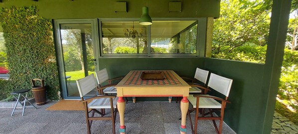 Une table d’échecs avec quatre chaises, un mur vert et une fenêtre donnant sur un jardin.
