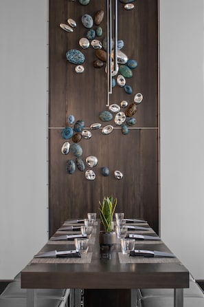 A dining table with a dark wood finish, surrounded by a variety of decorative stones and a potted plant. - AC Hotel Charlotte Ballantyne (Charlotte)