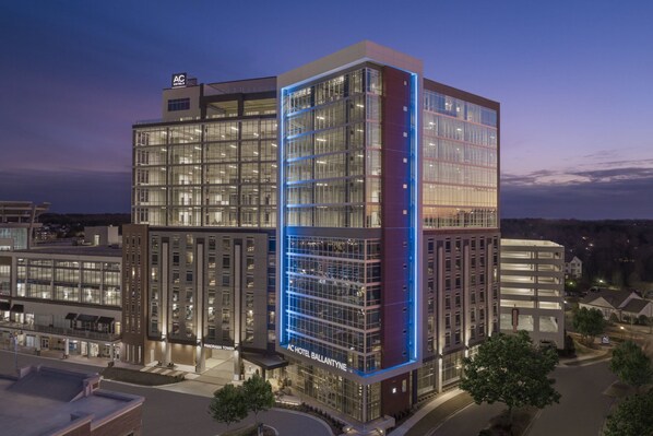 A modern hotel with a prominent glass facade, multiple floors, and a well-lit entrance.