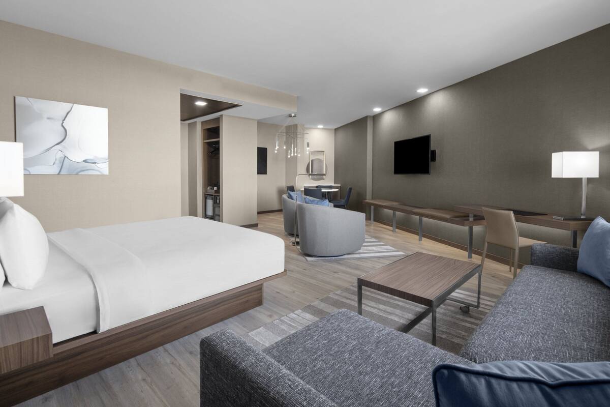 Een moderne hotelkamer met een groot bed, een bank, een bureau en een eethoek.