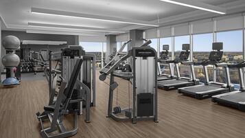 A modern gym with treadmills, weight machines, and a view of the city.